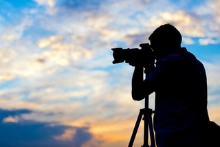 夕日の中で写真を撮る写真家のシルエット※画像はイメージです （Tijana/stock.adobe.com）