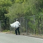 道路脇で、大きな袋を抱えながら歩く」ワイシャツにスラックス姿の男性の姿が…