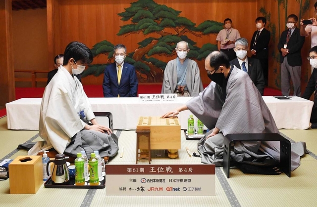 王位戦第４局で初手を指す木村一基王位（右）。左は藤井聡太棋聖＝１９日午前、福岡市中央区の大濠公園能楽堂