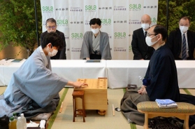 第６１期王位戦第１局で、初手を指す初挑戦の藤井聡太七段（現棋聖）。右は初防衛戦となる木村一基王位＝愛知県豊橋市のホテルアークリッシュ豊橋