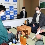 立会人の淡路仁茂九段から封じ手を示される藤井聡太棋聖（左）。奥は木村一基王位＝５日午前、神戸市北区有馬町、旅館「中の坊瑞苑」（撮影・後藤亮平）