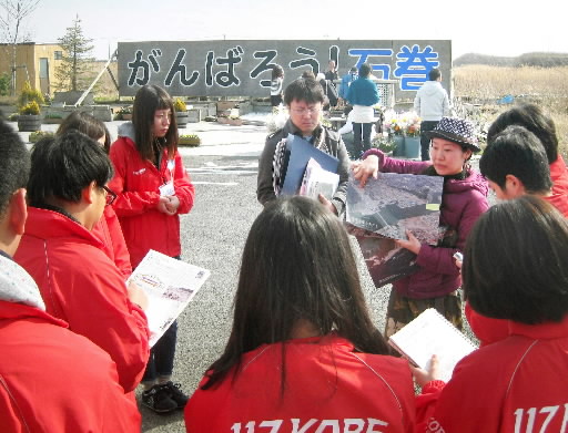 「がんばろう！石巻」の看板前で、当時の様子を聞くぼうさい委員会のメンバー＝石巻市内