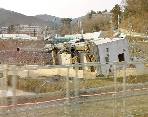 移動中の車内から。建物が基礎から横倒しに。今なお震災・津波の爪痕が点在している＝牝鹿郡女川町