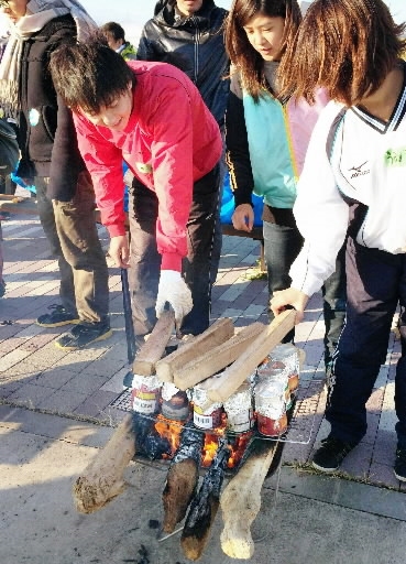 避難所体験会で缶詰を温める大学生たち＝２０１４年１１月２日、神戸空港