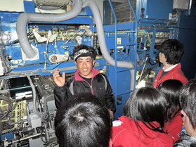 津波で全損したが復旧させたノリ加工機の前で、ノリ製造の説明を聞く。中央は経営者の相澤充さん＝石巻市渡波町