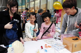ワークショップに参加した子どもに、非常持ち出し袋の中身を選んでもらう大学生＝神戸市中央区東川崎町１