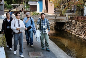 但馬最古とされる石橋が架かる水路沿いを歩く分科会メンバー＝朝来市和田山町竹田