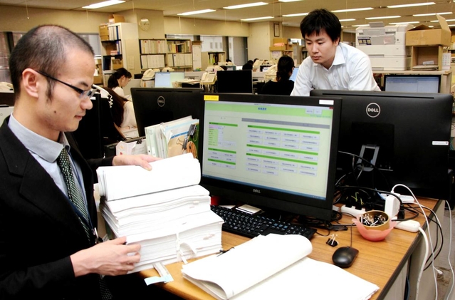 ベンチャー企業の関係者（右奥）の協力を得て、レセプトのチェック作業を自動化した＝神戸市役所