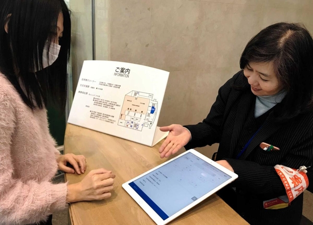 タブレットを使い、窓口案内する職員（右）＝神戸市東灘区役所