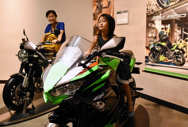 大型バイクの人気シリーズ「Ｎｉｎｊａ（ニンジャ）」（手前）と「Ｚ」に乗車する親子＝いずれも神戸市中央区波止場町、カワサキワールド