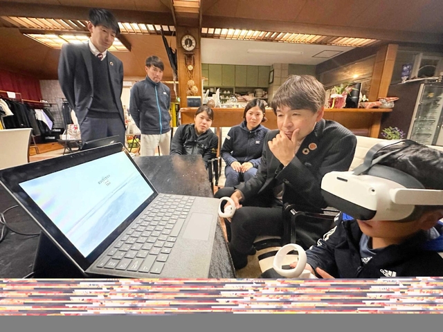 ＶＲ用ゴーグルを着け、能力を測定するゲームに取り組む小学生（右端）とドスカスの落合康ＣＴＯ（右から２人目）＝神戸市垂水区桃山台４、ロイヤルヒル’８１テニスクラブ