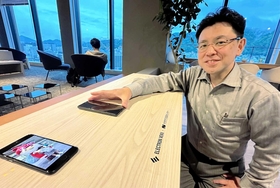 特許技術を搭載したスマートテーブルでスマホを充電する池内社長＝アンカー神戸