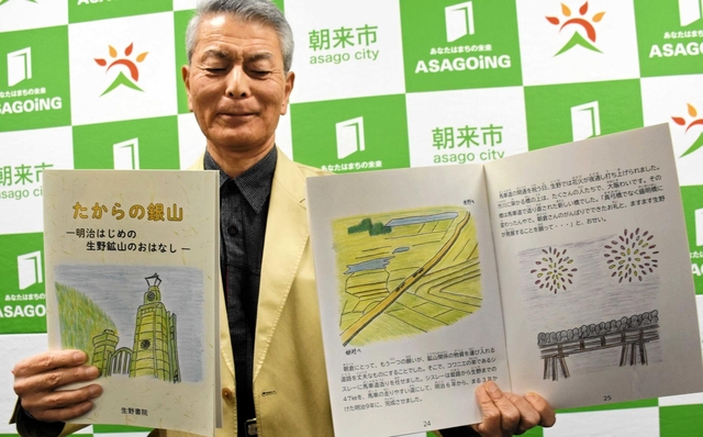 明治初期の生野鉱山を描いた絵本を手にする生野書院の岡田淳館長＝朝来市役所