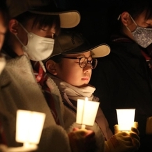 ろうそくのあかりを手に黙とうする子どもら＝１７日午前５時４６分、神戸市東灘区本山北町３、本山第一小学校