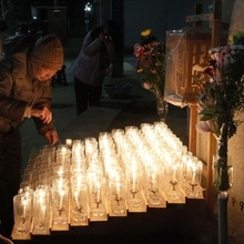 石碑の前に供えられたろうそくに火をともす人ら＝１７日午前５時３５分、神戸市長田区若松町１０、若松鷹取公園