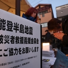 震災の追悼式典会場では能登半島地震への支援が呼びかけられ、募金後に手を合わせる人が見られた＝１７日午前６時５１分、神戸市中央区日吉町５、日吉町ポケットパーク