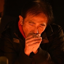 竹灯ろうをじっと見つめる男性＝１７日午前６時２９分、神戸市中央区加納町６、東遊園地（撮影・大田将之）