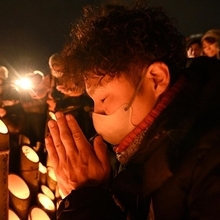 竹灯ろうに向けて手を合わせる男性＝１７日午前５時２２分、神戸市中央区加納町６、東遊園地（撮影・大田将之）