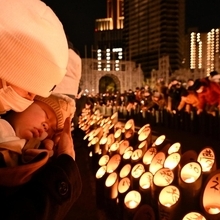 竹灯ろうの前で目を閉じる親子＝１７日午前６時５分、神戸市中央区加納町６、東遊園地（撮影・大田将之）