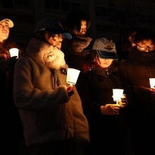 黙とうを終え、ろうそくの小さな炎を見つめる追悼行事の参加者たち＝１７日午前５時４８分、神戸市東灘区本山北町３、本山第一小（撮影・三浦拓也）