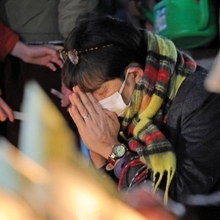 竹灯籠の灯りに祈る人＝１７日午前６時２６分、神戸市中央区加納町６、東遊園地（撮影・中西幸大）