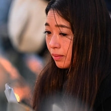 竹灯籠を見つめて涙を流す女性＝１７日午前６時５７分、神戸市中央区加納町６、東遊園地（撮影・風斗雅博）