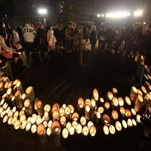 竹灯籠の周りに集まる参加者たち＝１７日午前６時２０分、神戸市中央区加納町６、東遊園地（撮影・丸山桃奈）