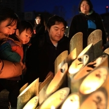 灯りを見つめる親子＝１７日午前６時２９分、神戸市中央区加納町６、東遊園地（撮影・丸山桃奈）