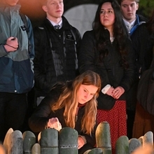 竹灯籠に火をともす外国人とみられる女性＝１７日午前６時１７分、神戸市中央区加納町６、東遊園地（撮影・風斗雅博）