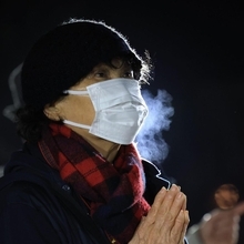 白い息を吐きながら、犠牲者に祈りをささげる女性＝１７日午前５時５４分、西宮市奥畑、西宮震災記念碑公園（撮影・吉田敦史）