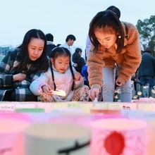 キャンドルに火をともしていく親子＝１７日午後５時１９分、神戸市中央区加納町６、東遊園地（撮影・鈴木雅之）