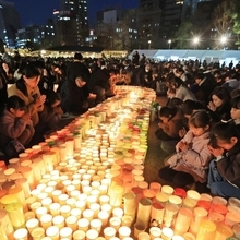 灯ろうを囲んで祈りをささげる人たち＝１７日午後５時４６分、神戸市中央区加納町６、東遊園地（撮影・吉田敦史）