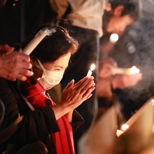 ろうそくを手に、祈る女性＝１７日午前６時２分、神戸市中央区加納町６、東遊園地（撮影・鈴木雅之）