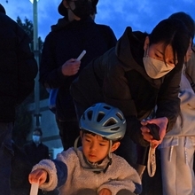 犠牲者を追悼するロウソクに火をともす人たち＝１７日午後５時３０分、神戸市長田区若松町４、ＪＲ新長田駅前（撮影・風斗雅博）
