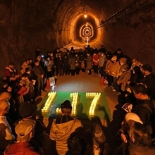 １．１７の形に並べたＬＥＤ照明を囲んで黙とうする人たち＝１７日午後１時２５分、神戸市兵庫区湊川町９、湊川隧道（撮影・斎藤雅志）