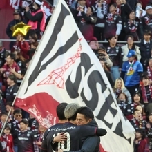 ２連覇を決め、抱き合う吉田監督（右）と大迫。後ろにはヴィッセル神戸の旗がはためく＝ノエビアスタジアム神戸（撮影・笠原次郎）