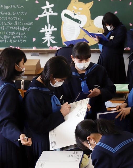 チョークアートで彩られた黒板の前で、卒業を喜ぶ中学生たち。思いを込めた言葉を交わし合う＝神戸市内