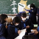 チョークアートで彩られた黒板の前で、卒業を喜ぶ中学生たち。思いを込めた言葉を交わし合う＝神戸市内