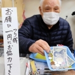 日々、大量の小銭を扱うという花崎治良さん。レジ前の立て札で協力を求める＝神戸市兵庫区東山町１