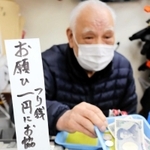日々、大量の小銭を扱うという花崎治良さん。レジ前の立て札で協力を求める＝神戸市兵庫区東山町１