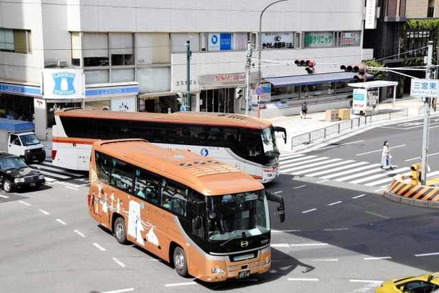 交差点を左折しようとするバス（奥）。横断歩道を渡る歩行者も多く、車の渋滞が常態化している＝神戸市中央区