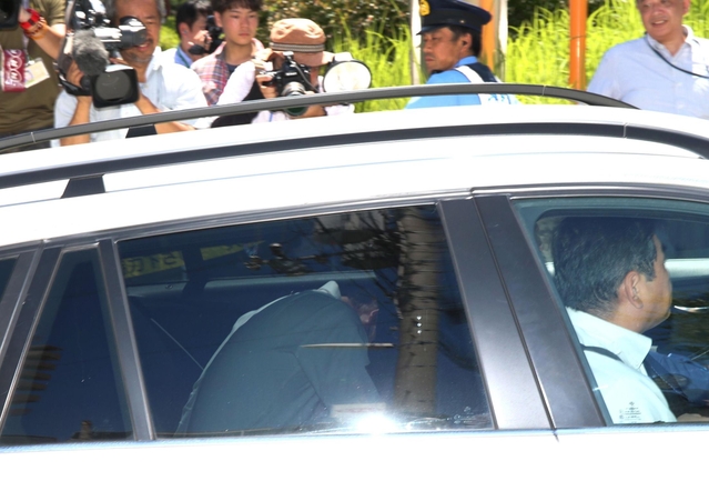車両の後部座席で顔を伏せて神戸地裁に入る野々村竜太郎被告（手前左）＝６日午後１時４８分、神戸市中央区、神戸地裁前