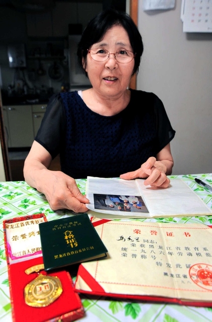 中国で優秀な教師に贈られたメダルを前に半生を語る松倉秀子さん＝尼崎市内