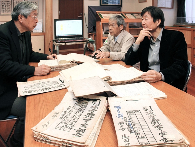 引揚者在外事実申告書を見る藤岡司理事長（右）ら兵庫県海外同友会のメンバー＝神戸市中央区海岸通３