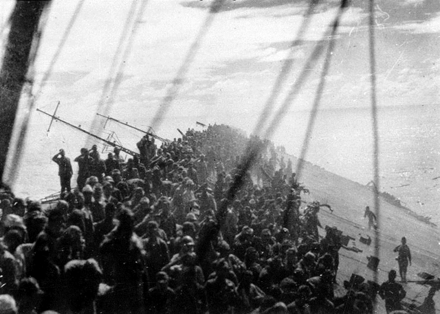 沈没直前、甲板が大きく傾く空母「瑞鶴」。降ろされる軍艦旗に敬礼する乗組員の姿が見える＝１９４４年１０月２５日、フィリピン・エンガノ岬沖