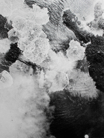 情島（右）のそばで、米軍の爆撃を受け煙に包まれる「日向」（米国立公文書館所蔵）
