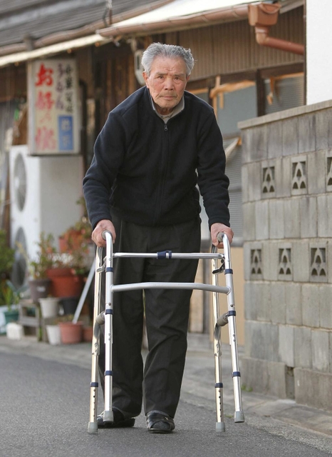歩行器をついて、自宅前を歩く片山省さん。部隊でただ一人、今を生きる＝洲本市上物部（撮影・峰大二郎）