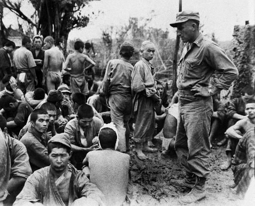 収容所に集められた日本人捕虜を監視する米軍兵＝１９４５年６月２０日、沖縄県（県公文書館提供）