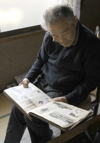 戦時中の写真を見つめる片山省さん＝洲本市上物部（撮影・峰大二郎）