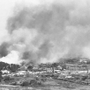 空襲を受け、煙を上げて炎上する市街地＝１９４５年、那覇市（沖縄県公文書館提供）
